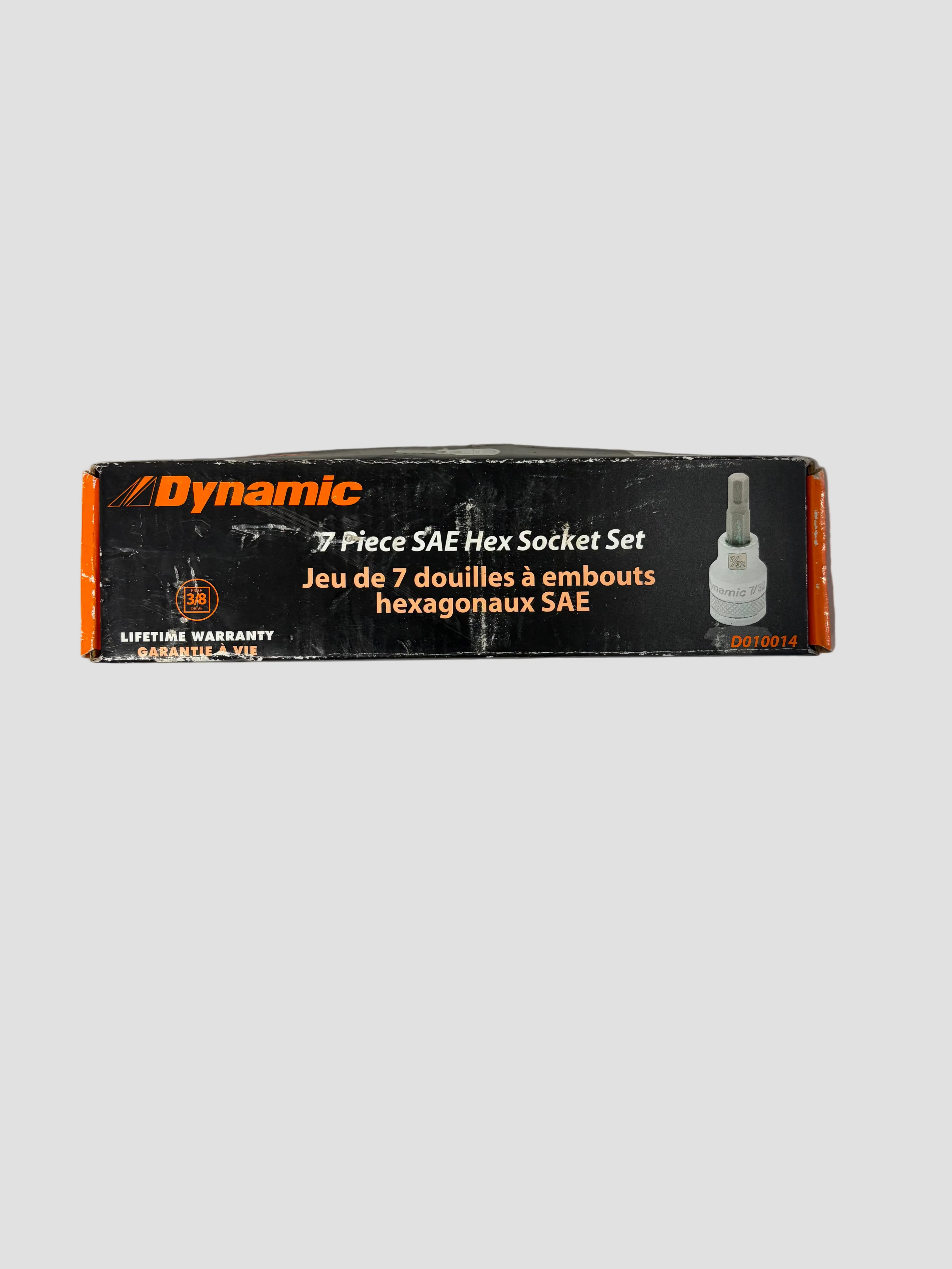 A rectangular black box with orange edges labeled “Dynamic 7 Piece SAE Hex Socket Set.” The text appears in both English and French, and there’s an image of a single hex socket tool on the right side. The box also displays a “Lifetime Warranty” badge and the product code “D010014.” It’s placed on a light gray surface.