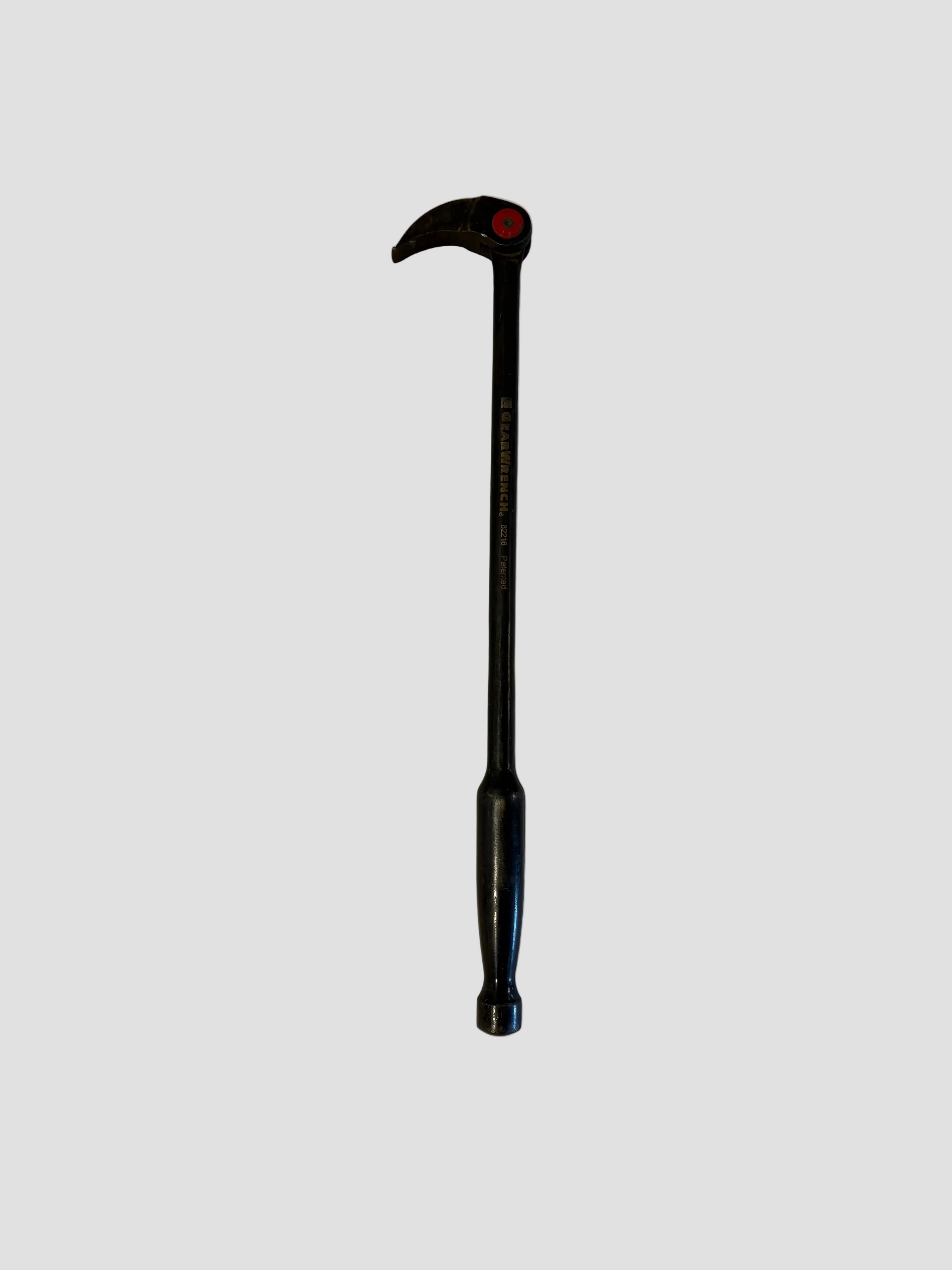 A black GearWrench indexing pry bar resting on a light-colored surface. The tool has a long, straight shaft with a rounded handle and a curved claw head featuring a red circular pivot point. The text “GEARWRENCH 82248 12" INDEXING PRY BAR” is printed along the shaft, indicating its brand and model. The pry bar’s sturdy steel construction and adjustable head design make it suitable for prying and lifting tasks in mechanical or construction work.