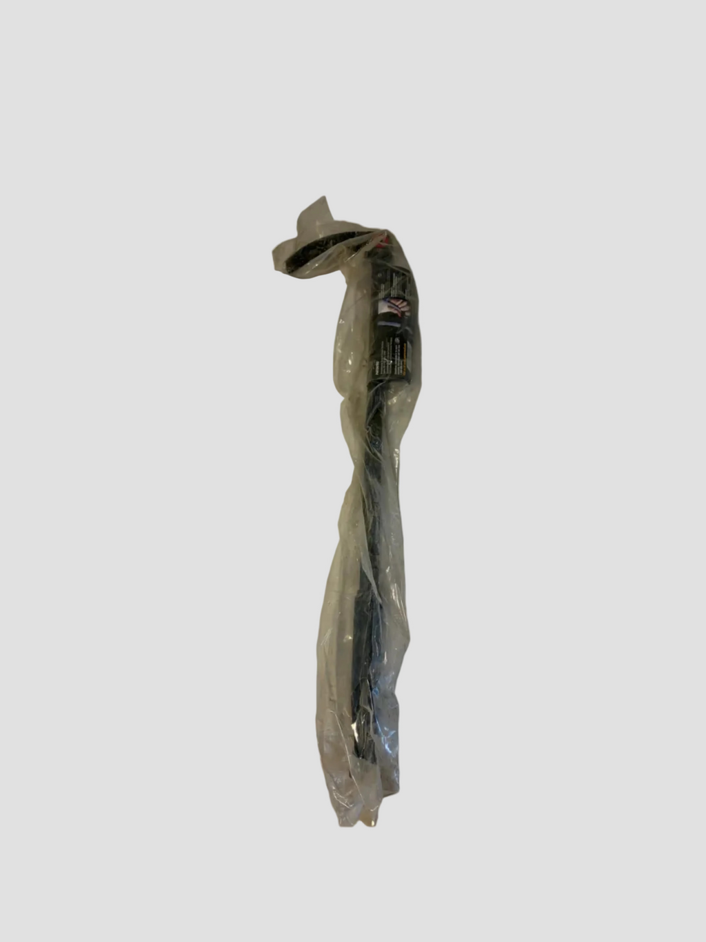 A long black cable or cord wrapped in clear plastic packaging, standing against an off-white wall above a beige tiled floor.
