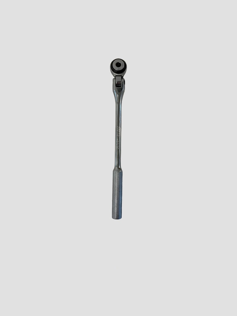 A chrome Craftsman ratchet wrench lying on a light-colored surface. The wrench has a polished metallic finish with a long handle featuring a textured grip for better control. Its ratcheting head includes a square drive socket connector and a directional switch, reflecting light off its smooth surface.