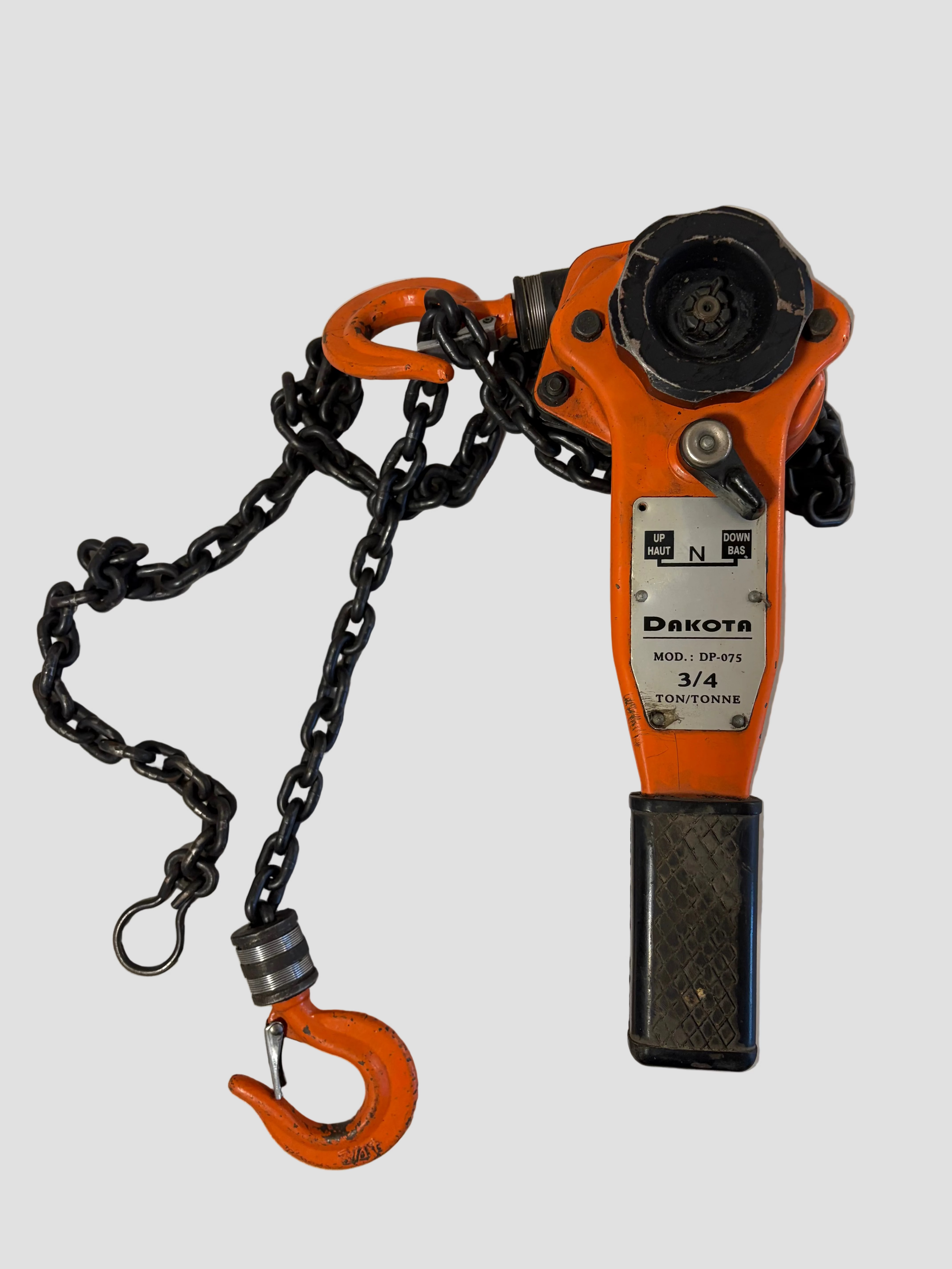 An orange and black DAKOTA 3/4 tonne chain hoist with a black chain and orange hook, photographed on a white surface.