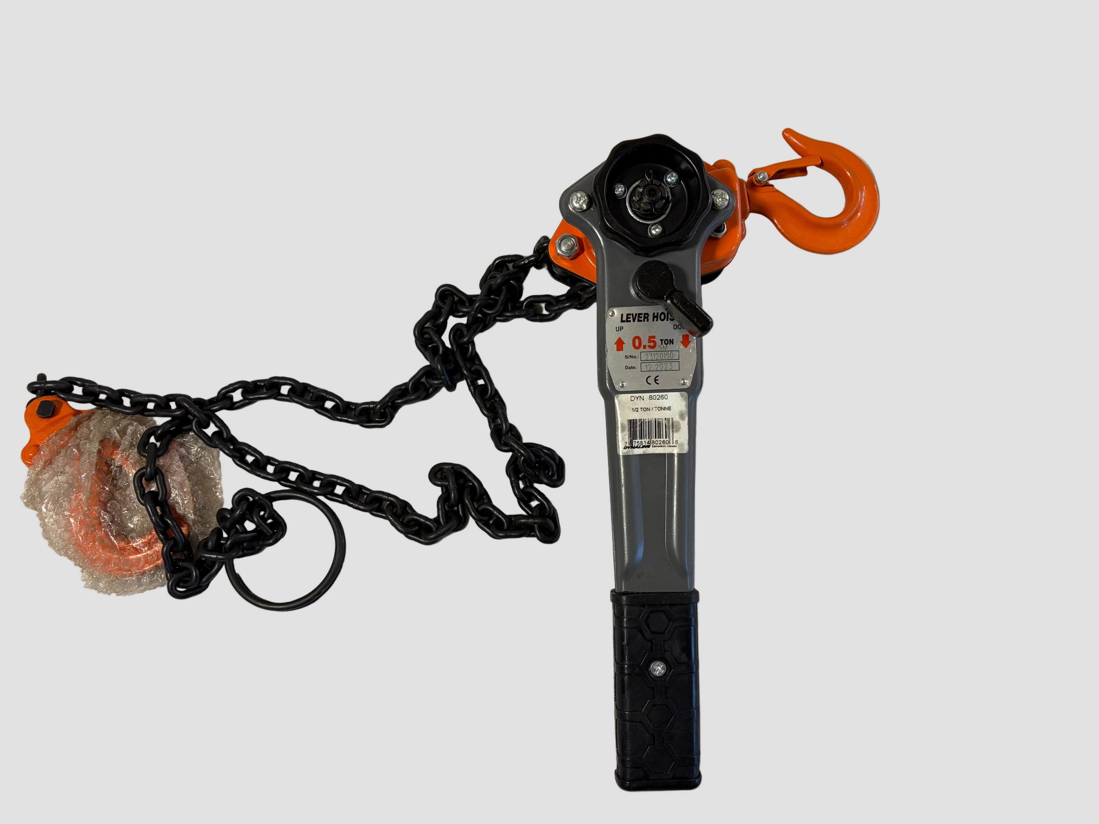 A manual chain hoist with an orange hook and black chain, shown on a plain off-white background with its plastic-wrapped orange hook still attached.