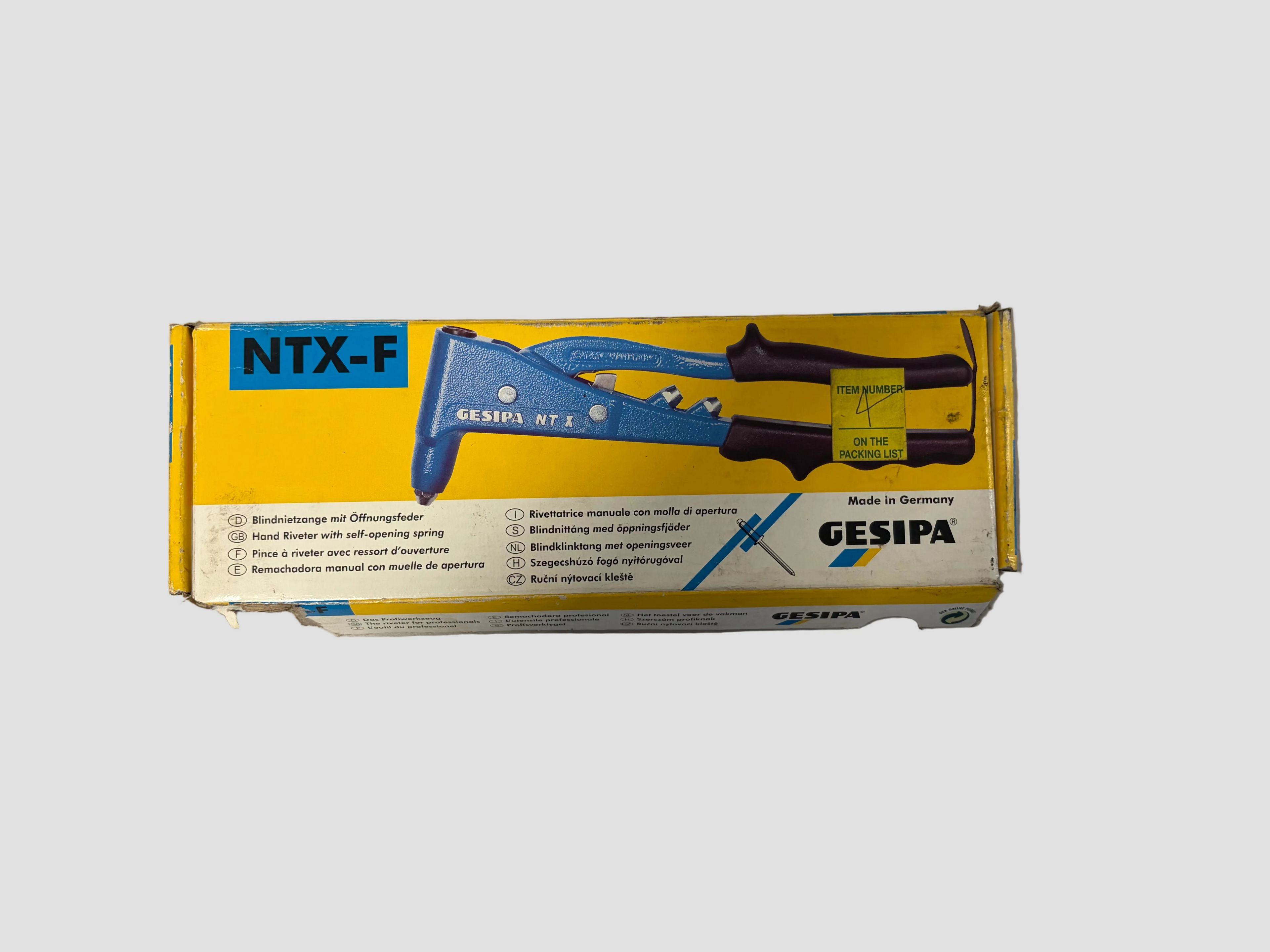 A yellow and white Gesipa NTX-F tool box containing a blue and black hand tool, photographed on a light gray surface.