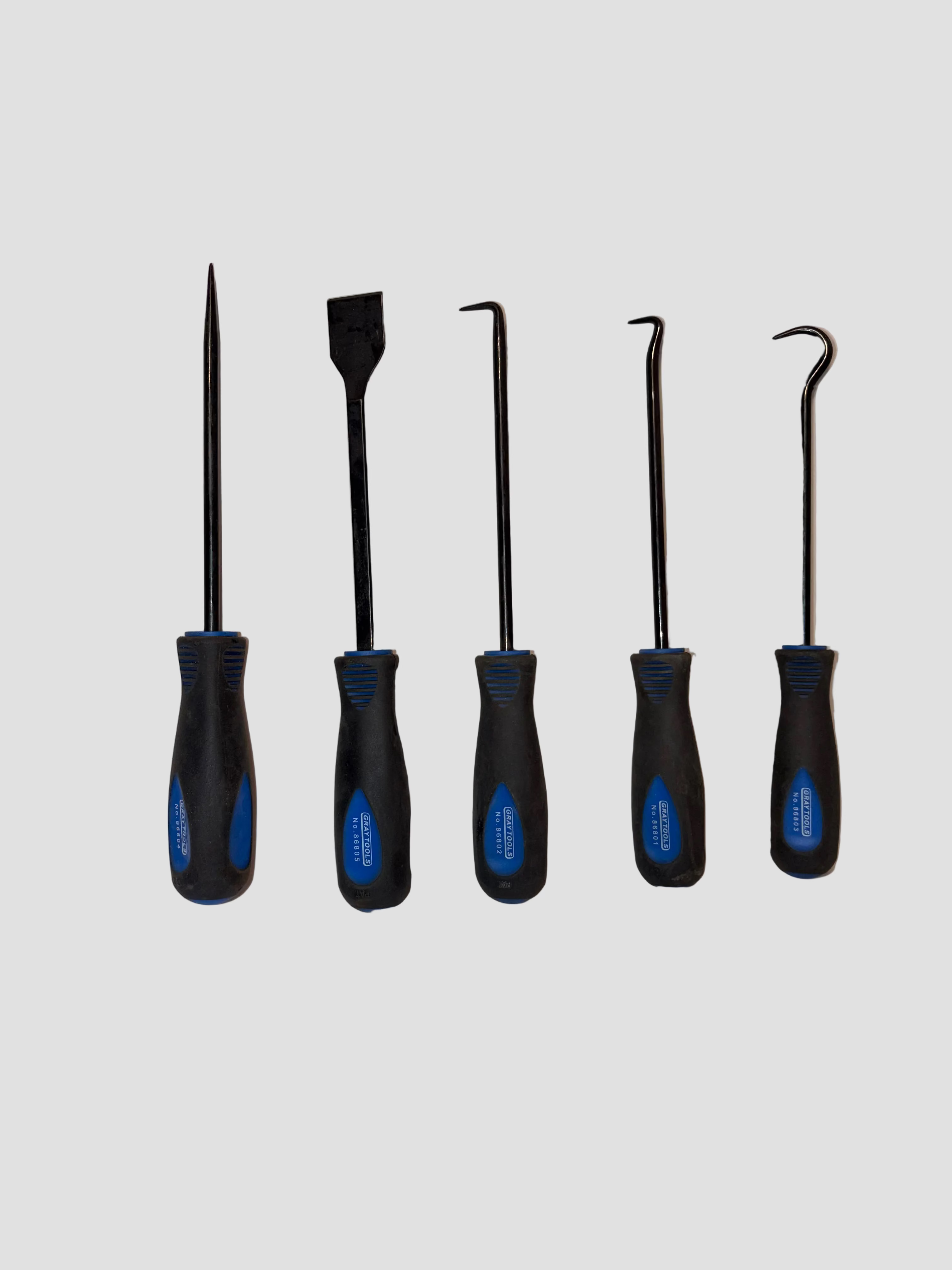 A set of five Craftsman hand tools arranged neatly on a light-colored surface. Each tool has a black handle with blue accents and a metal shaft. From left to right: a pointed pick, a flat scraper, a right-angle pick, a curved pick, and a hook pick. The handles are labeled “CRAFTSMAN USA,” and the tools are designed for precision tasks such as cleaning, scraping, or retrieving small parts.