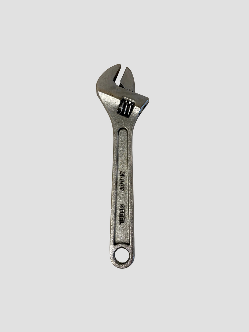 A silver adjustable wrench with a black adjustment lock, shown on a plain light gray surface.
