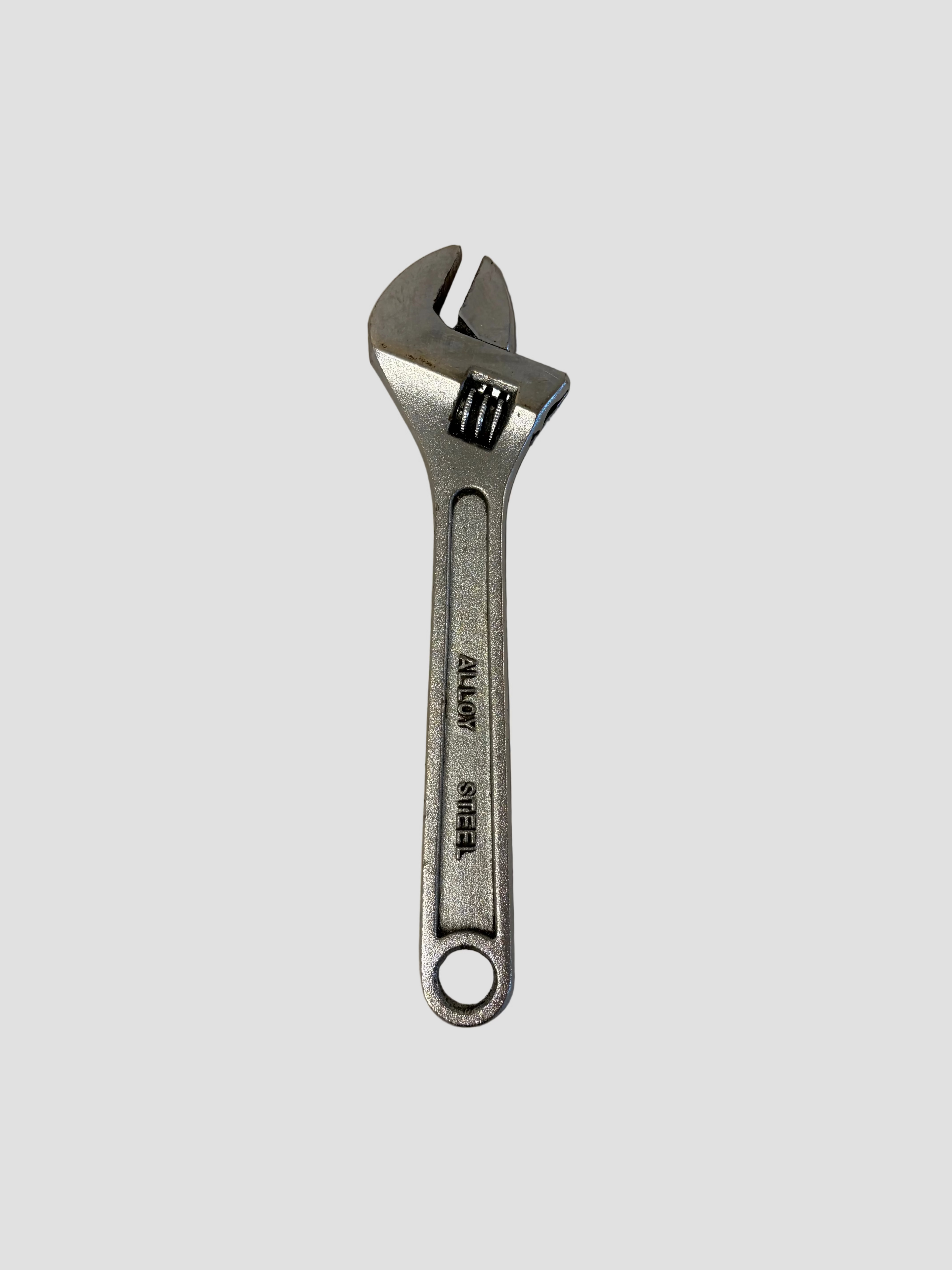 A silver adjustable wrench with a black adjustment lock, shown on a plain light gray surface.