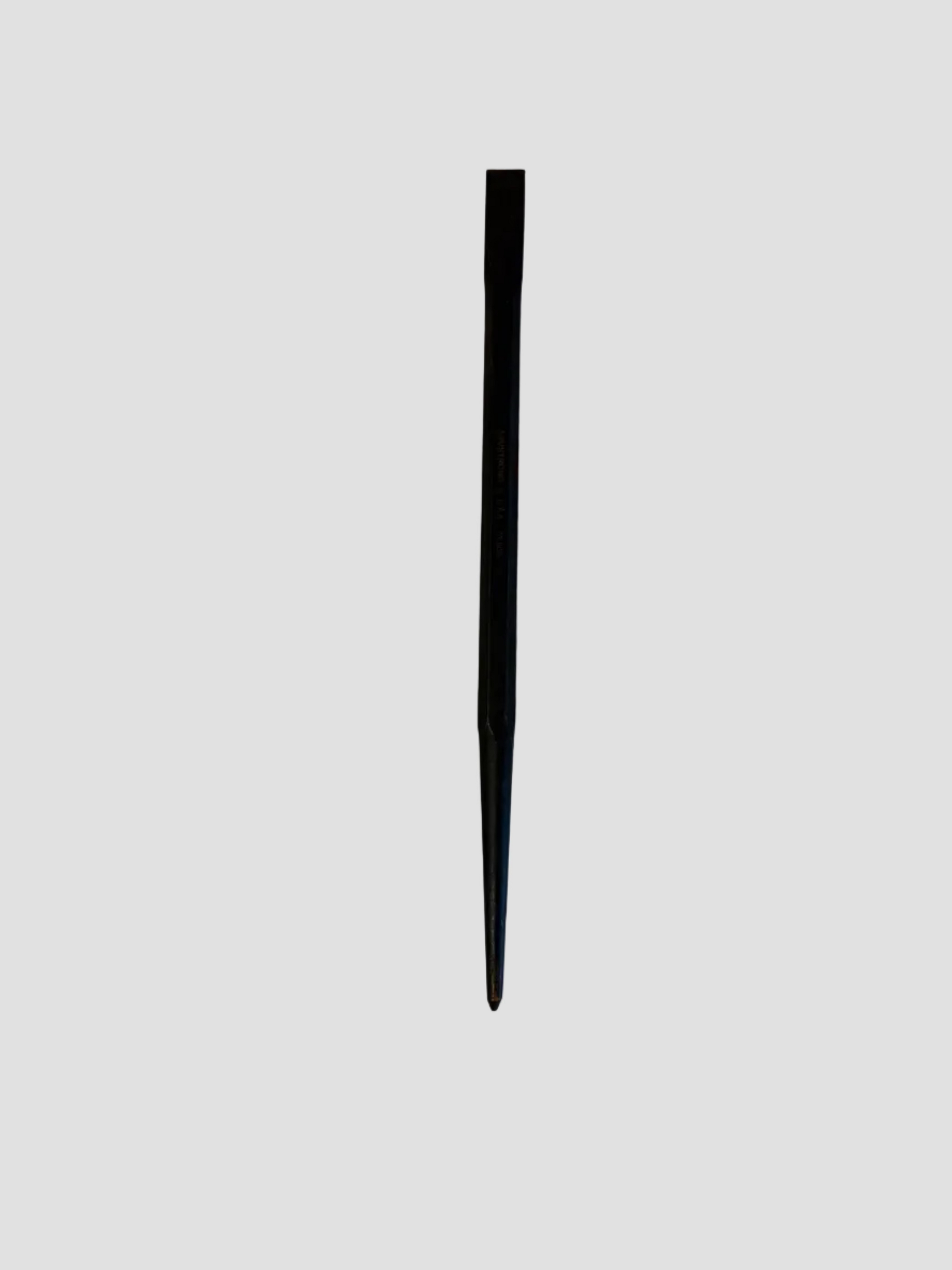 A single black metal tool, appearing to be a straight edge, spacer, or sharp pointed rod, standing vertically on a plain off-white surface.