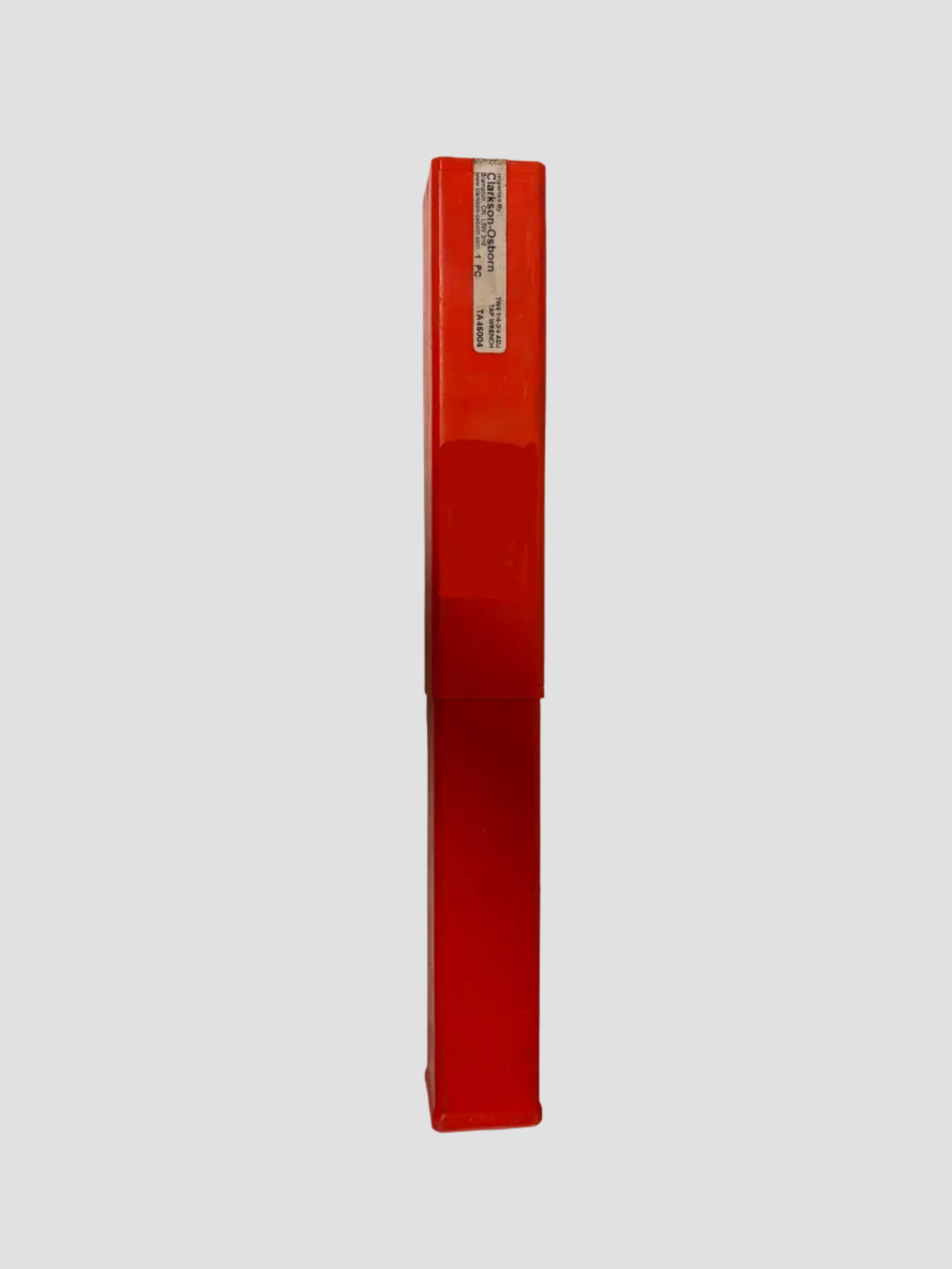 A bright red plastic cosmetic tube, likely a lip gloss or lipstick, standing vertically on a white surface with a soft shadow cast to the left.