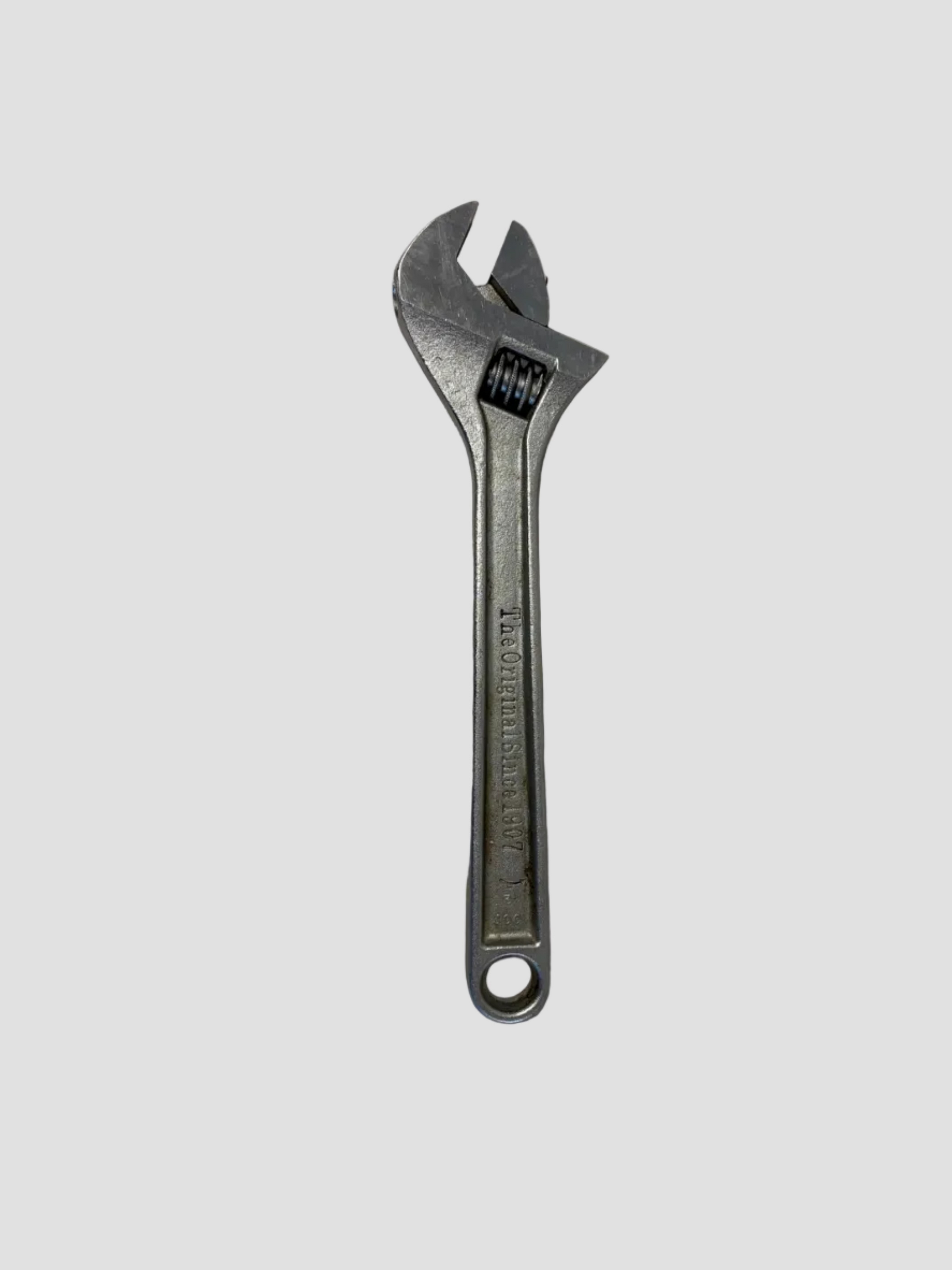 A silver adjustable wrench with a textured handle, photographed on a plain off-white surface.