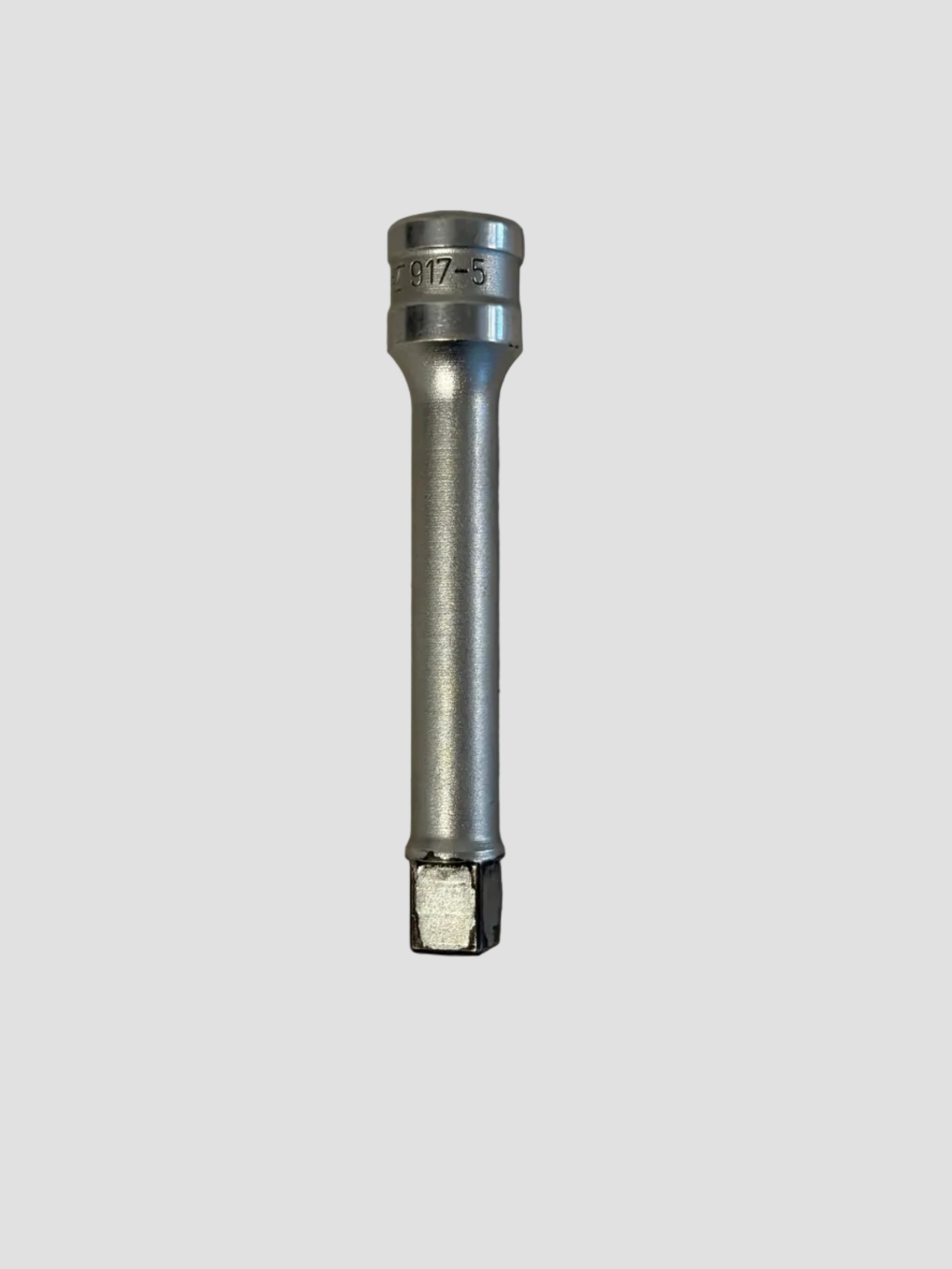 A silver deep socket tool resting on a light-colored surface. The socket has a long cylindrical body with a hexagonal drive end and a recessed opening at the opposite end for fitting over nuts or bolts. The upper section is engraved with the marking “917-5,” indicating its size or model number. The polished metal finish and extended length suggest it’s designed for reaching fasteners in tight or recessed spaces, commonly used with a ratchet or impact wrench.