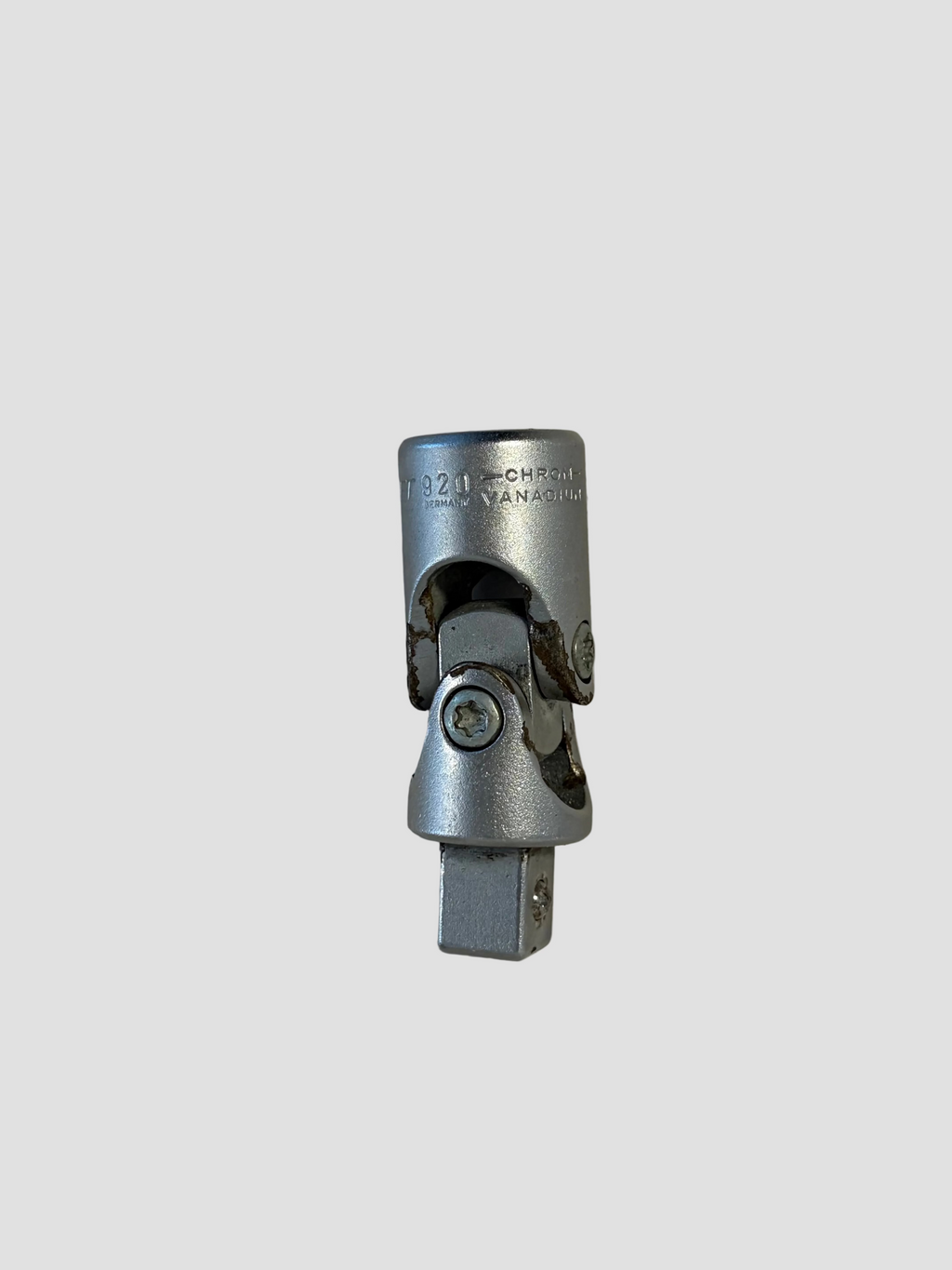A silver metal splined connector or adapter with a hexagonal female end, photographed on a plain off-white surface.