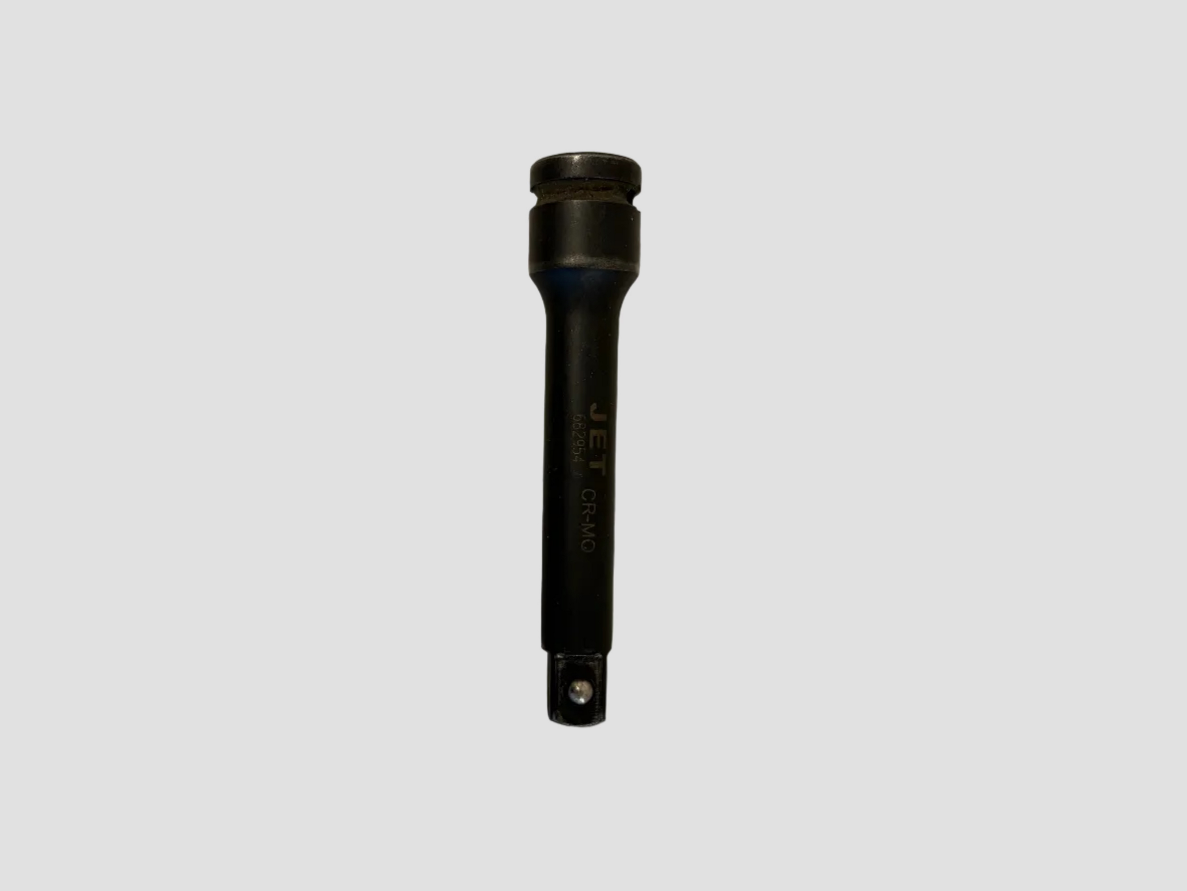 A black JET 1/4 inch socket tool with a textured grip and gold lettering, lying on a light gray surface.