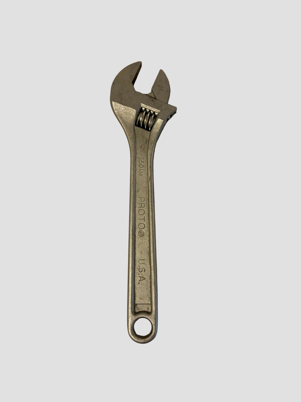 A silver metal adjustable wrench with a loop at the end, photographed on a plain off-white surface.